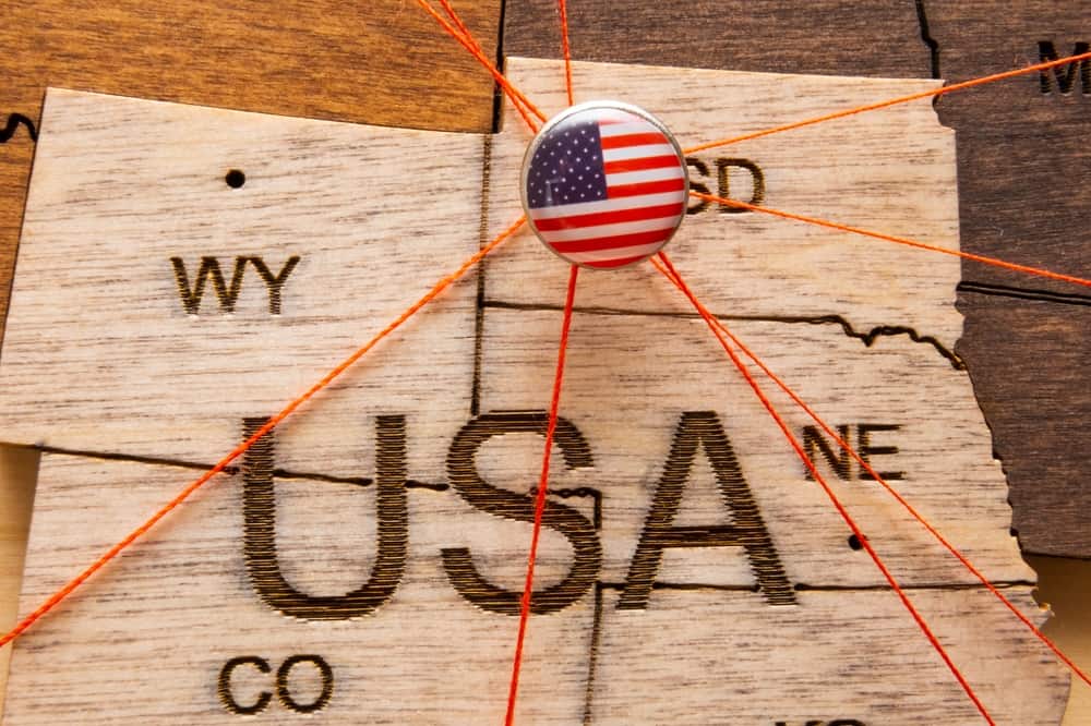 A wooden map of some states with an American flag button connected to orange strings