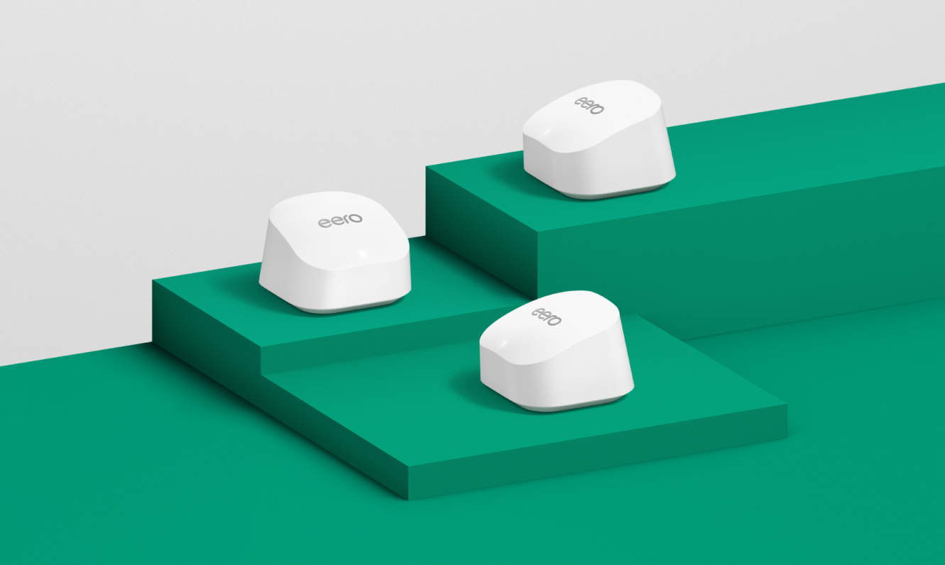 Three white eero 6+ devices displayed on green risers of varying heights.