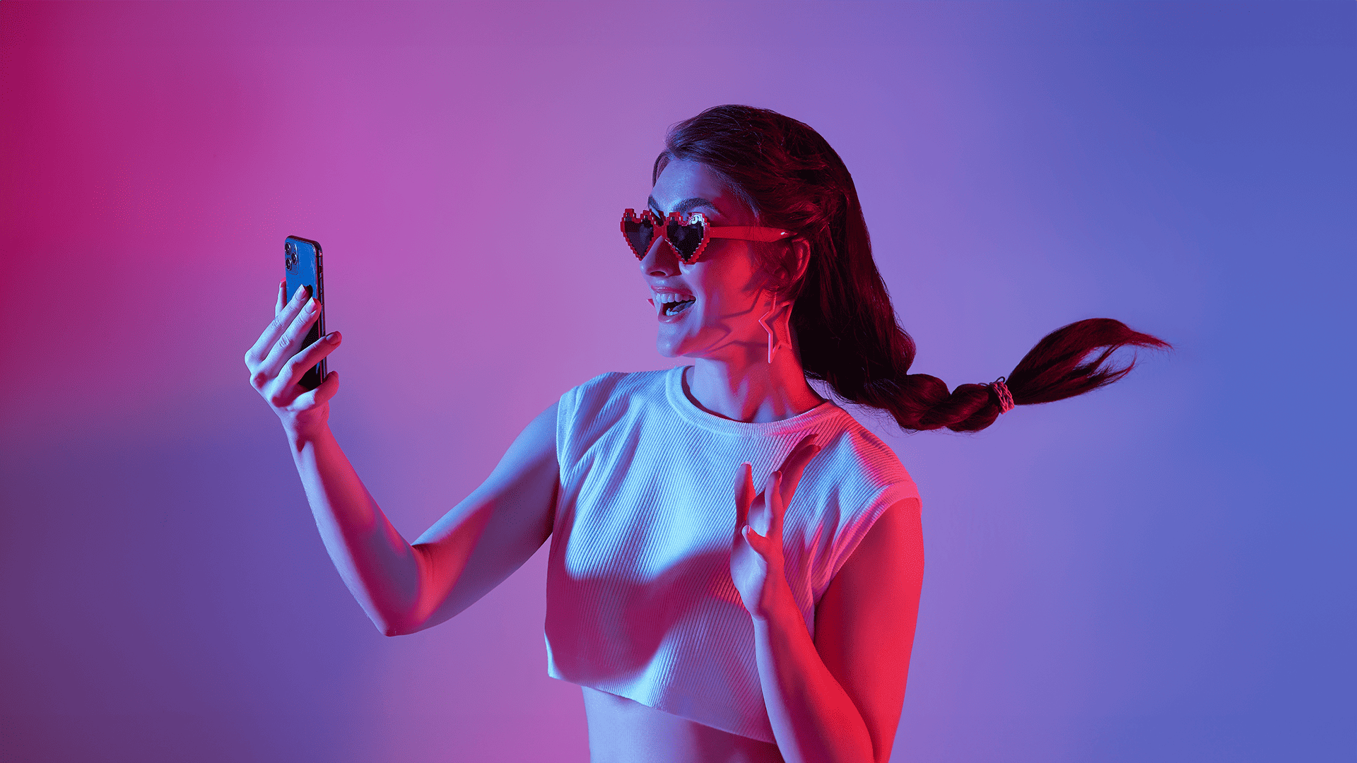 Woman in heart-shaped sunglasses amazed by her cell phone