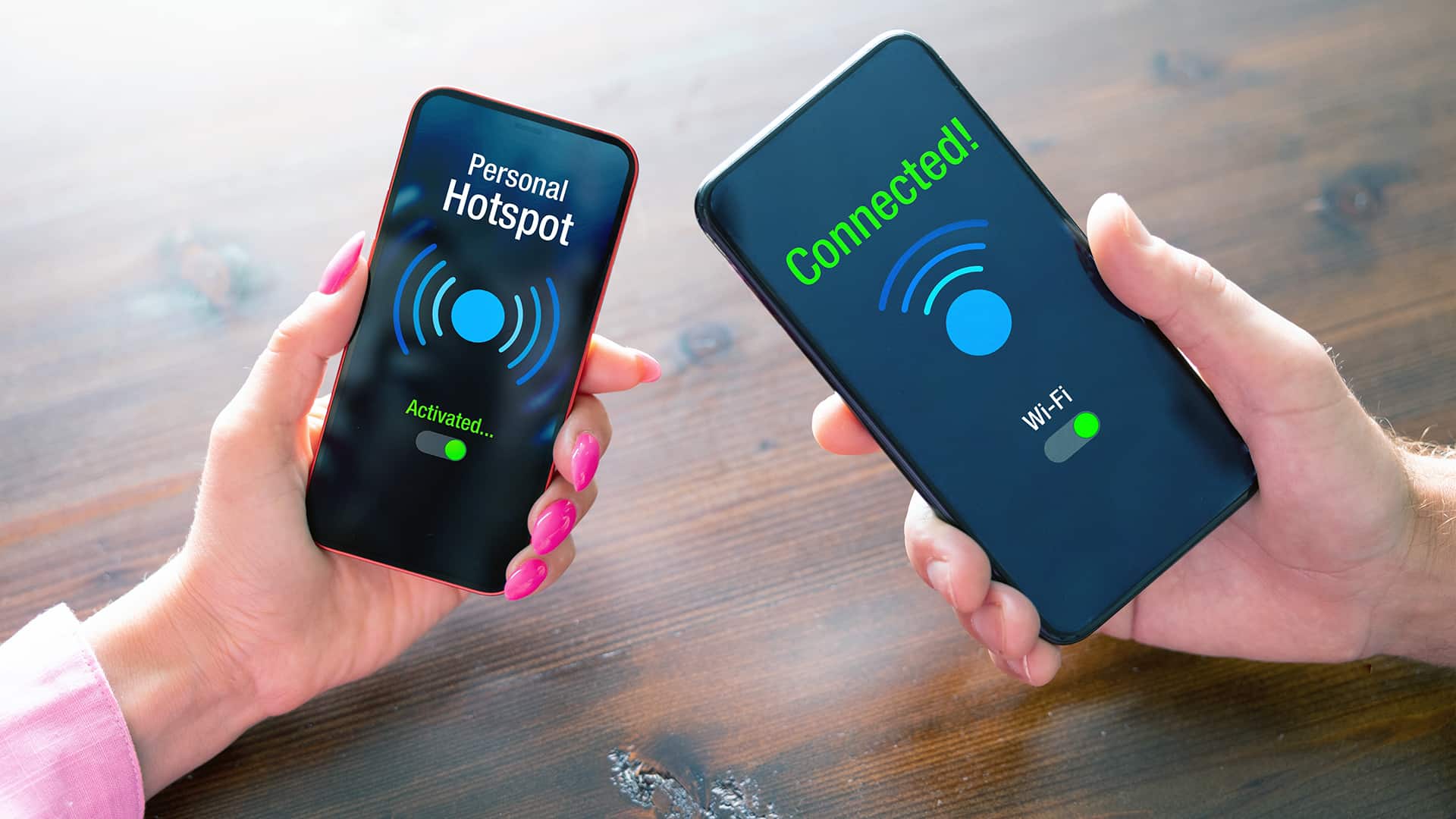Two people hold phones, one as a hotspot and one connected to the hotspot