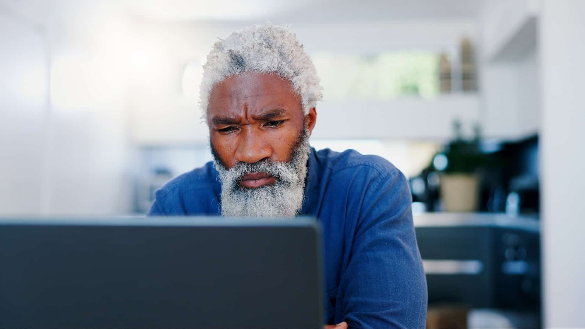 A man frowning while using a laptop in this image from Shutterstock.