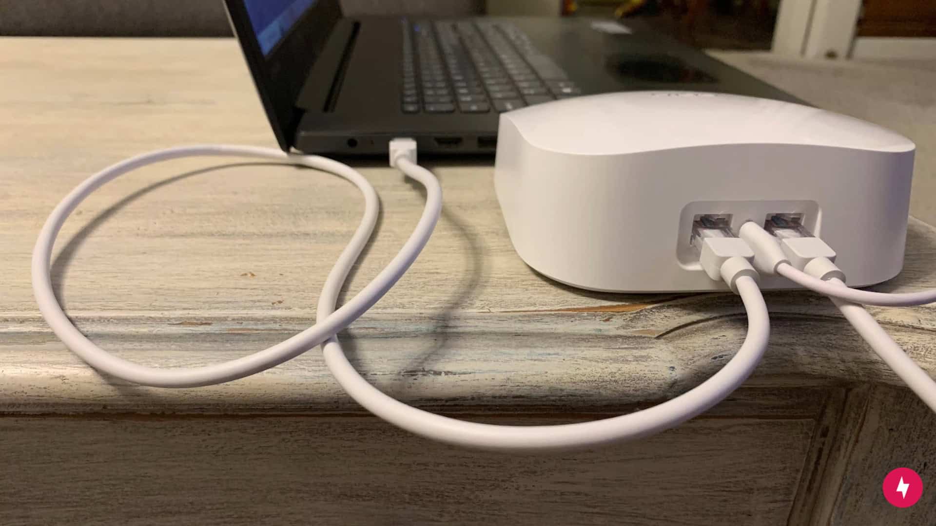 An Ethernet cord beside an Ethernet port on a white Eero router.