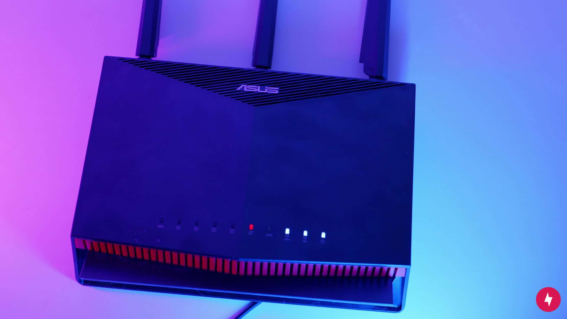 An Asus RT-AX86U Pro router on a pink and blue background.