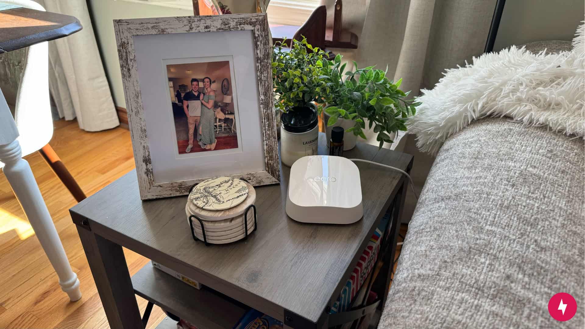 An eero 7 node placed on a wooden table next to a framed photo.